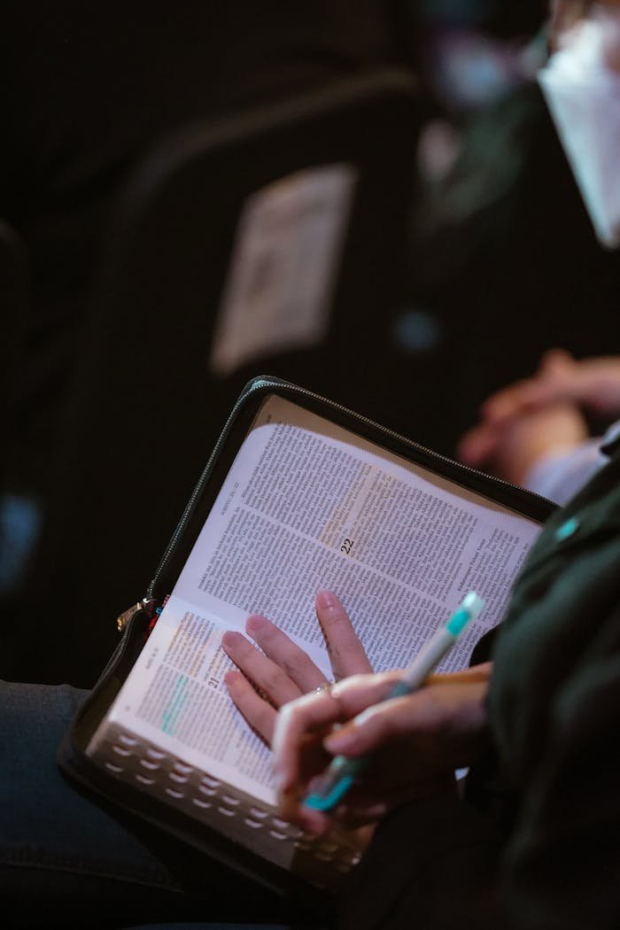 A person writes in a book while attending a seminar, emphasizing education and focus.